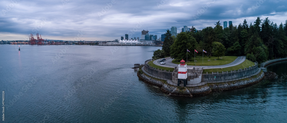 Brockton Point Lighthouse in Stanley Park, with Vancouver Downtown, BC, Canada, in the background. Taken during a cloudy morning sunrise. Aerial Panorama