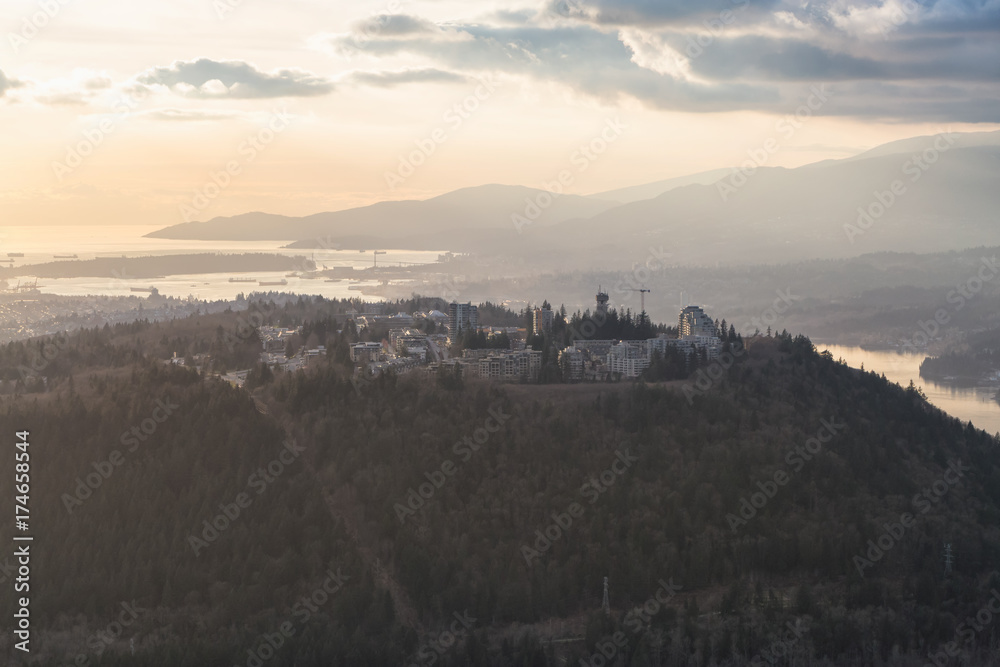 Aerial view on Burnaby Mountain and Simon Fraser University (SFU), with Vancouver City in the Background. Picture taken in British Columbia, Canada, during a cloudy sunset.