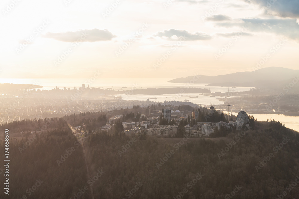 Aerial view on Burnaby Mountain and Simon Fraser University (SFU), with Vancouver Downtown in the Background. Picture taken in British Columbia, Canada, during a cloudy sunset.