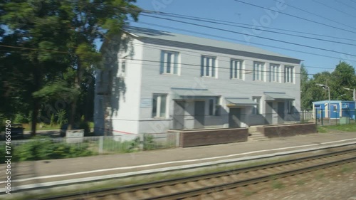 POV: High-speed Train fast moves past a railway station in a town in the summer photo