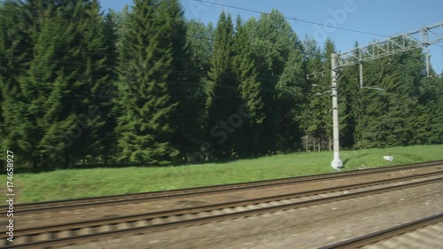 POV: High-speed Train fast moves past a forest and a railway in the summer photo