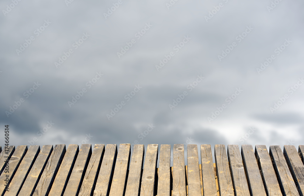 Old wooden table for a total blurred background the sky with clouds.