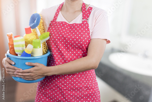 woman with cleaning equipment ready to clean house on bathroom background