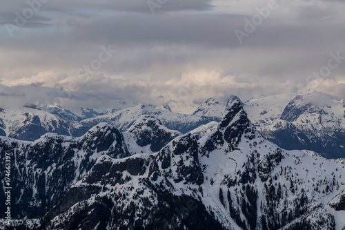 Aerial landscape view of beautiful mountain range with cloud layers during sunset. Taken in a remote area North of Sunshine Coast, British Columbia, Canada.