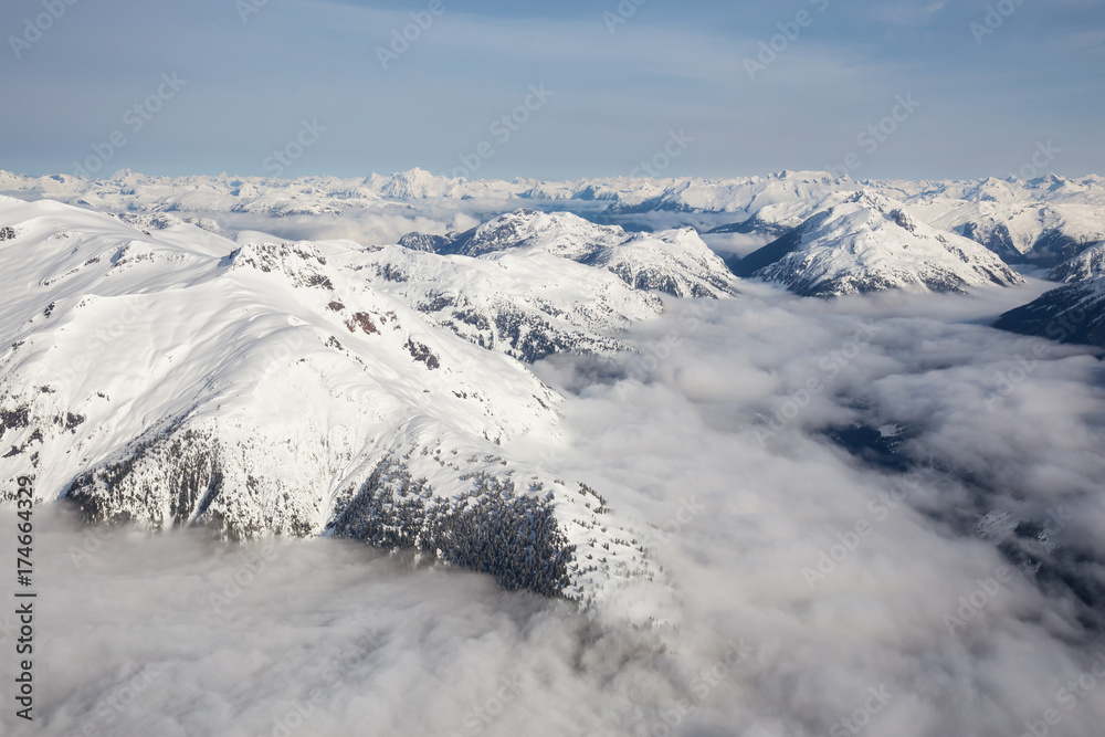 Beautiful aerial landscape view of the snow covered mountain range with a low level cloud. Taken in the remote area early morning North West from Vancouver, British Columbia, Canada.