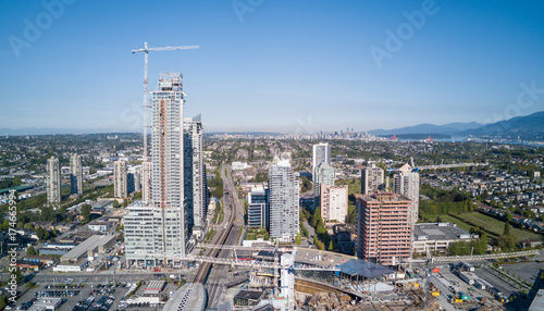 Aerial view of a big construction site at a mall with skytrain and appartment buildings in the vicinity. Taken in Burnaby, Vancouver City, British Columbia, Canada.