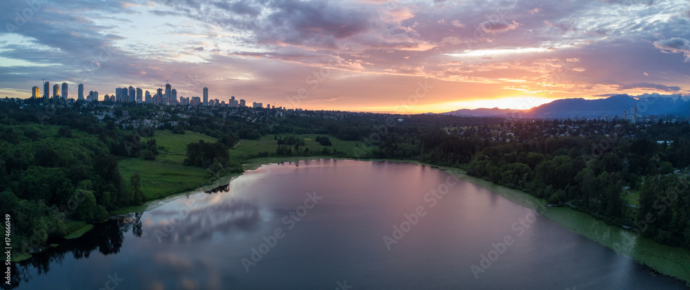 Aerial View of Deer Lake Park with Metrotown City Skyline in the backgournd. Taken in Burnaby, Greater Vancouver, British Columbia, Canada, during a cloudy sunset. Aerial View of Deer Lake Park with Metrotown City Skyline in the backgournd. Taken in Burnaby, Greater Vancouver, British Columbia, Canada, during a cloudy sunset.
