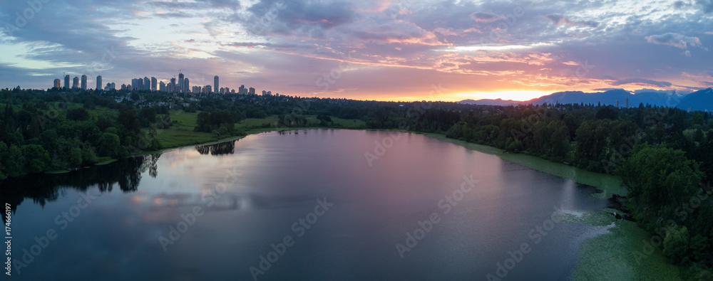 Aerial View of Deer Lake Park with Metrotown City Skyline in the backgournd. Taken in Burnaby, Greater Vancouver, British Columbia, Canada, during a cloudy sunset.