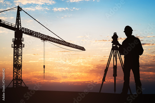 Surveyor Standing With Equipment At Construction Site photo