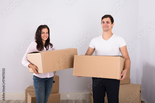 Young couple carrying cardboard boxes at new home
