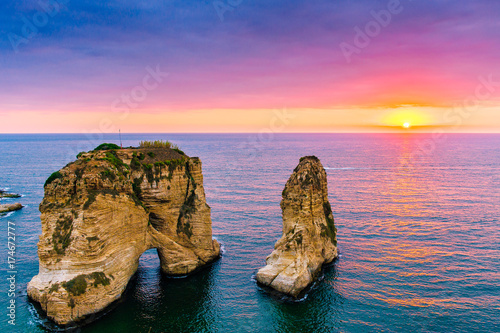 Beautiful sunset on Raouche, Pigeons' Rock. In Beirut, Lebanon.Sun and Stones are reflected in water.dense clouds in the sky.