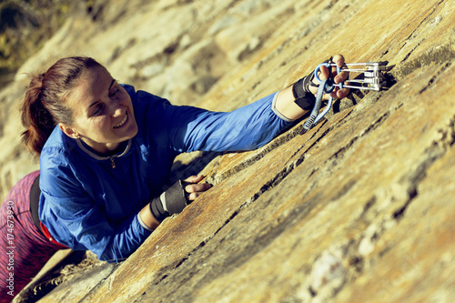 woman rock climber climbs on the cliff. rock climber climbs on a rocky wall. woman makes hard move. top view