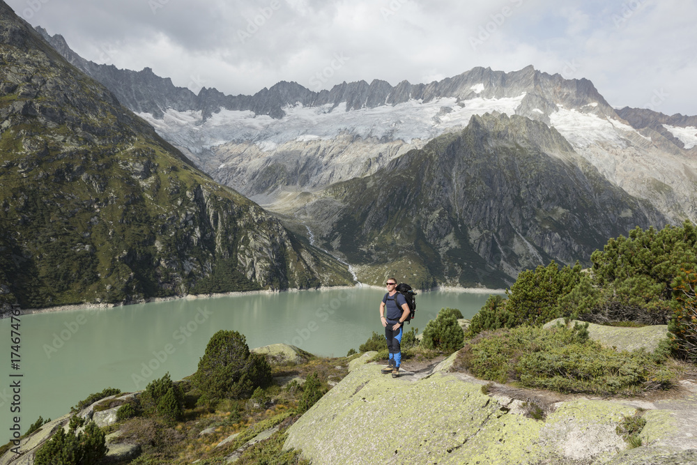 Hiker enjoys the breathtaking view of a mountain lake in the Swiss Alps