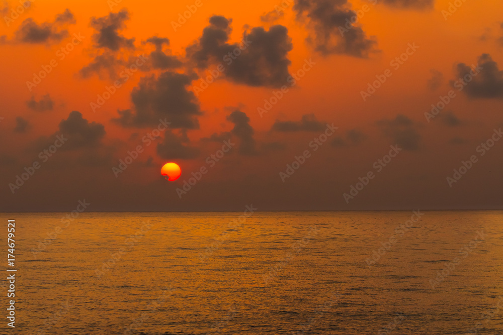 Beautiful orange sunset over the calm sea. Seashore with beautiful picturesque sky
