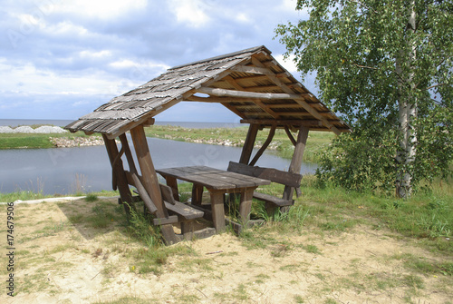 Equipped picnic place (wooden benches and canopy) on the lake shore.