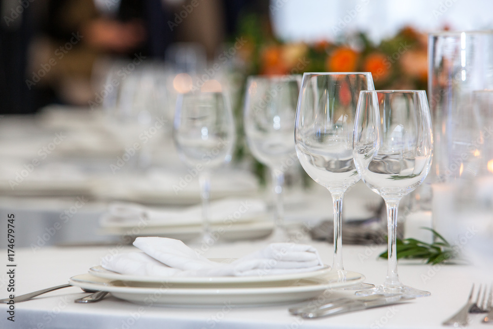 Table setting with glasses for different drinks on table on room background