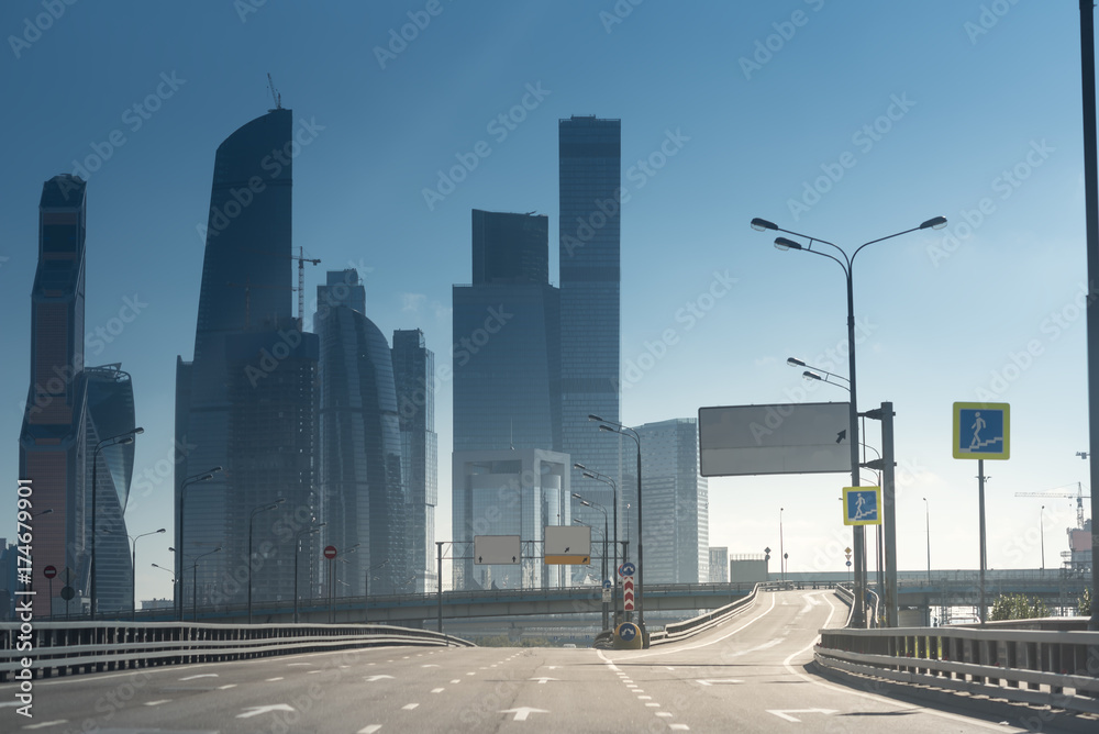 skyscrappers of a downtown and a huge empty highway under the sun. concept of strong financial performance and success.
