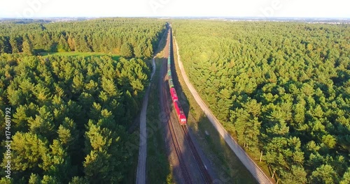 - AERIAL railway: Long cargo train transporting wagons across the autumn forest at sunset