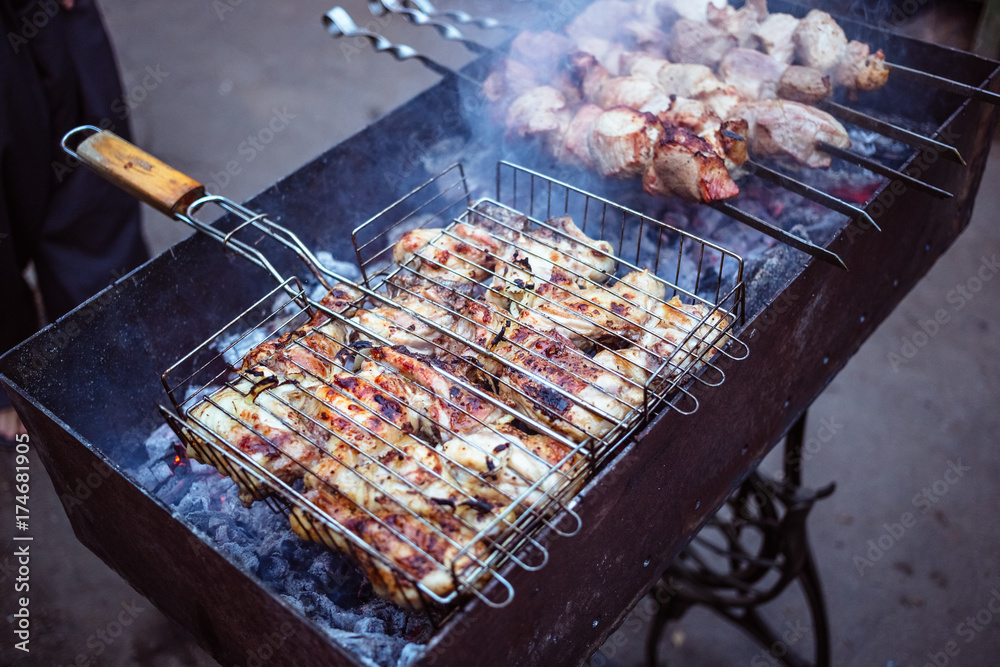 Grilled kebab cooking on metal grill frame. Roasted meat cooked at barbecue with smoke. Close up BBQ fresh chicken meat slices. Traditional eastern dish