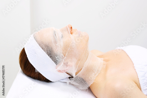 Maseczka nakładana na gazę. Kobieta w salonie kosmetycznym relaksuje się podczas zabiegu pielęgnacyjnego.