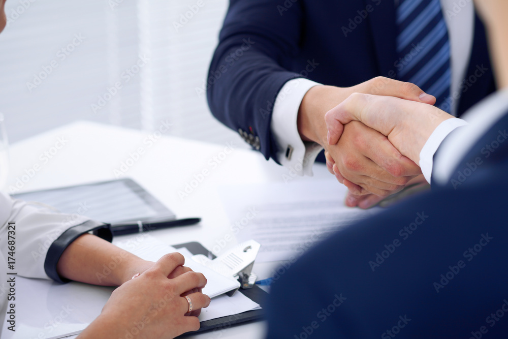 Business handshake at meeting or negotiation in the office, close-up. Partners are satisfied because signing contract or financial papers