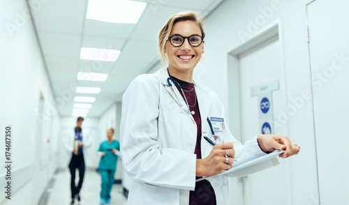 Female physician in hospital corridor writing prescription photo