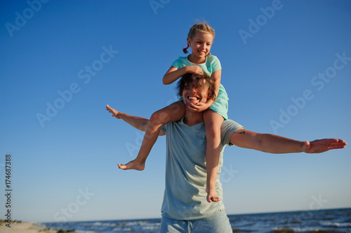 Young man gaily spends time with the little daughter by the sea.