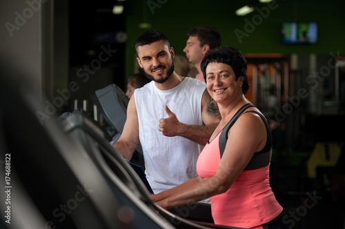 Male personal trainer with female client in gym