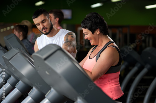 Fitness coach assisting his client on treadmill