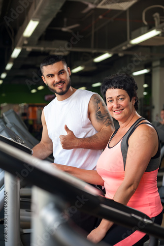 Smiling personal coach and female client in gym