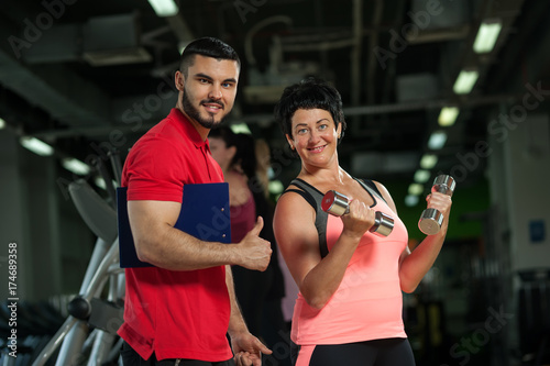 Cheerful middle aged woman exercising with coach