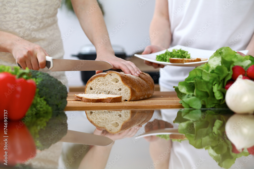 Close-up of human hands slicing bread in a kitchen. Friends having fun while cooking in the kitchen. Chef cook represent culinary masterclass Close-up of human hands slicing bread in a kitchen. Friends having fun while cooking in the kitchen. Chef cook represent culinary masterclass