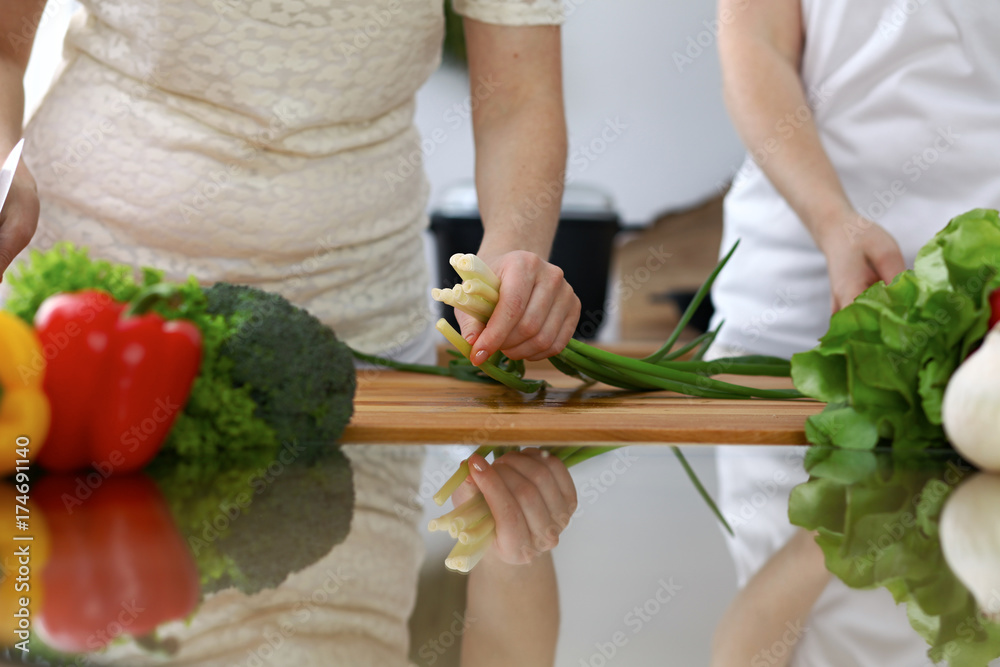 Close-up of human hands cooking in a kitchen. Friends having fun while preparing fresh salad. Vegetarian, healthy meal and friendship concept Close-up of human hands cooking in a kitchen. Friends having fun while preparing fresh salad. Vegetarian, healthy meal and friendship concept