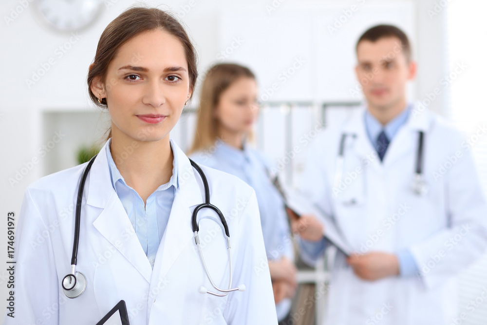 Young beautiful female doctor smiling on the background with patient in hospital Young beautiful female doctor smiling on the background with patient in hospital