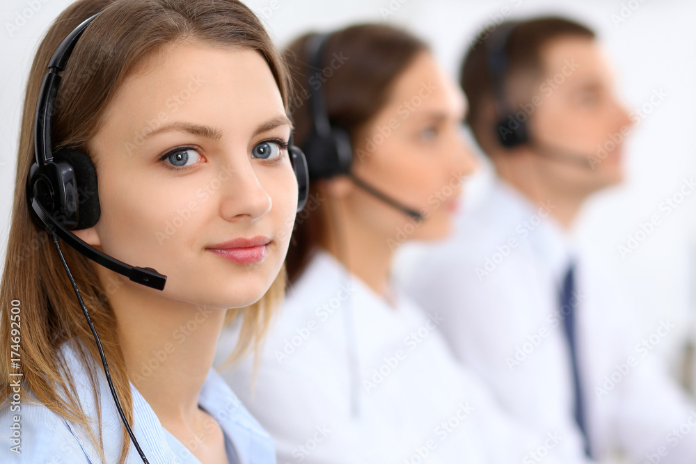Call center operators. Focus at young beautiful business woman in headset Call center operators. Focus at young beautiful business woman in headset