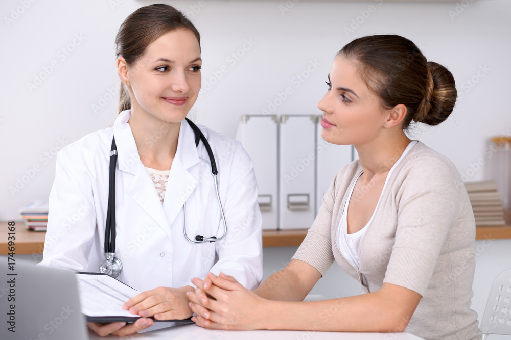 Doctor and patient sitting at the desk. The physician or therapist makes a diagnosis. Health care, medicine and patient service concept Doctor and patient sitting at the desk. The physician or therapist makes a diagnosis. Health care, medicine and patient service concept