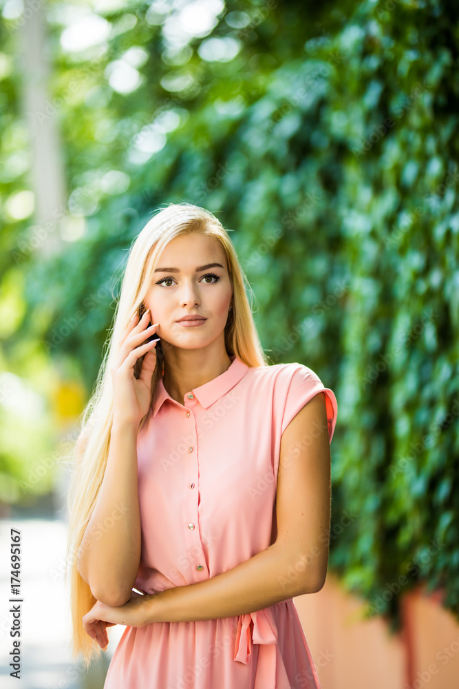 Young woman wearingdress over green leaves texture wall Young woman wearingdress over green leaves texture wall
