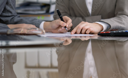Group of business people and lawyers discussing contract while sitting at the table. Woman chief is taking pen for signing papers. Close-up of human hands at work. Meeting or negotiation concept in