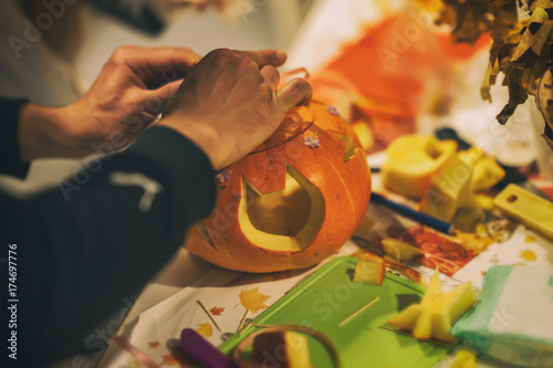 Cutting traditional ornaments from natural organic pumpkins for harvest holidays, Thanksgiving, Halloween, hands of men. Decoration of home family holidays