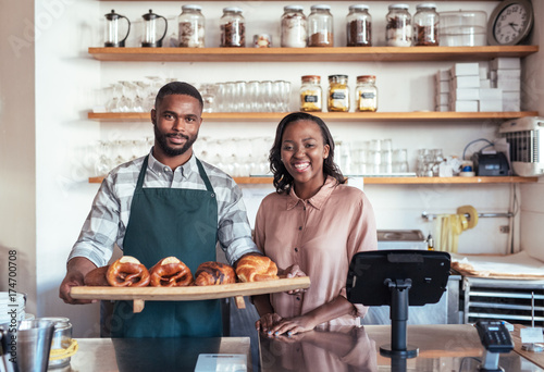 Fotografia Smiling African entrepreneurs with baked goods behind their bakery counter