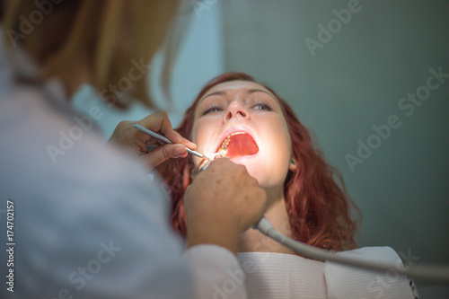 A young girl at a dentist, on a tooth examination, and beautiful teeth sitting on a dental chair, a dentist examines her teeth with her teeth