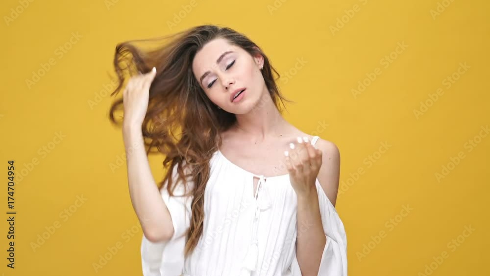 Pretty brunette woman in dress suffers from the heat over orange background Pretty brunette woman in dress suffers from the heat over orange background