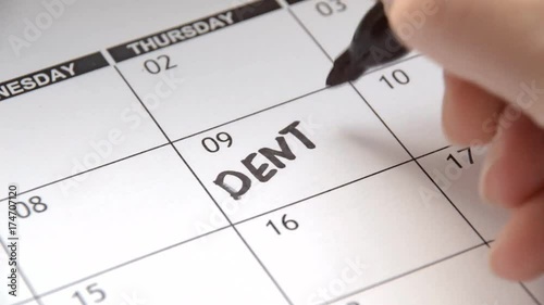 Writing DENTIST on calendar with a black marker