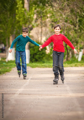 Fototapeta Naklejka Na Ścianę i Meble -  Three children on inline skates in park