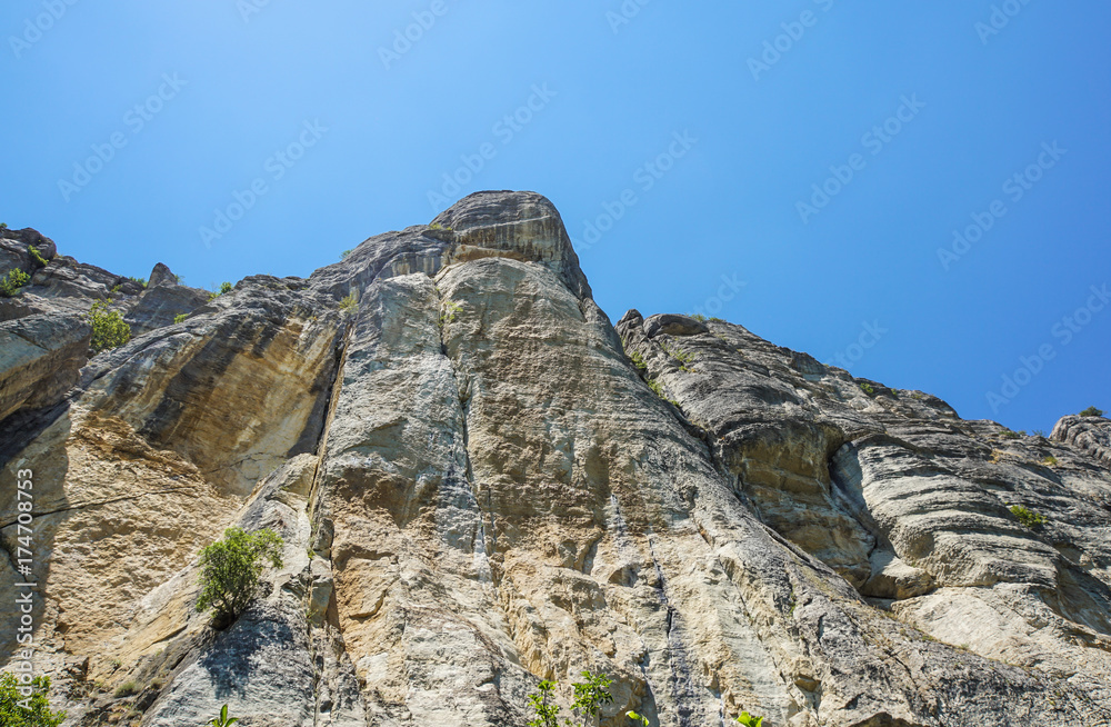 rocky wall of a mountain stretching up to the blue sky rocky wall of a mountain stretching up to the blue sky