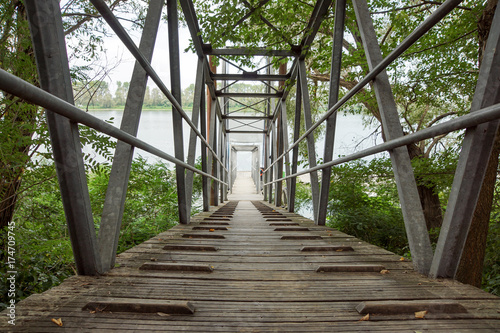 Fotografiet Wood and metal footbridge on the river in autumn