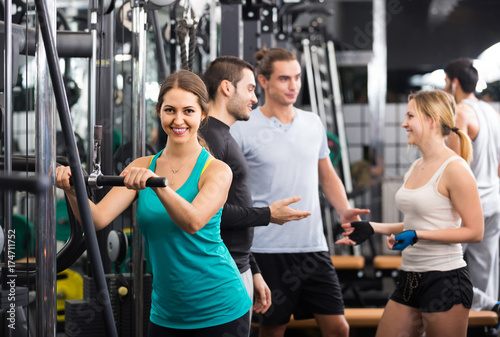 Adults having strength training under coach control in gym