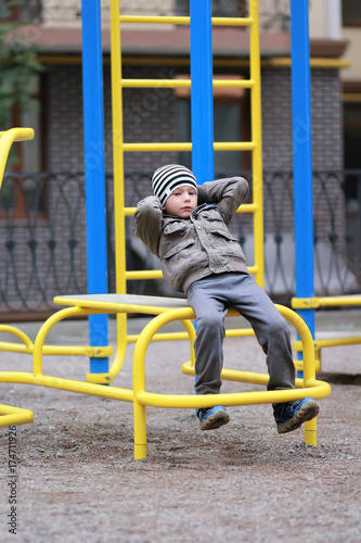 Five year old boy working out in the street, in the outdoor gym in the yard on the playground