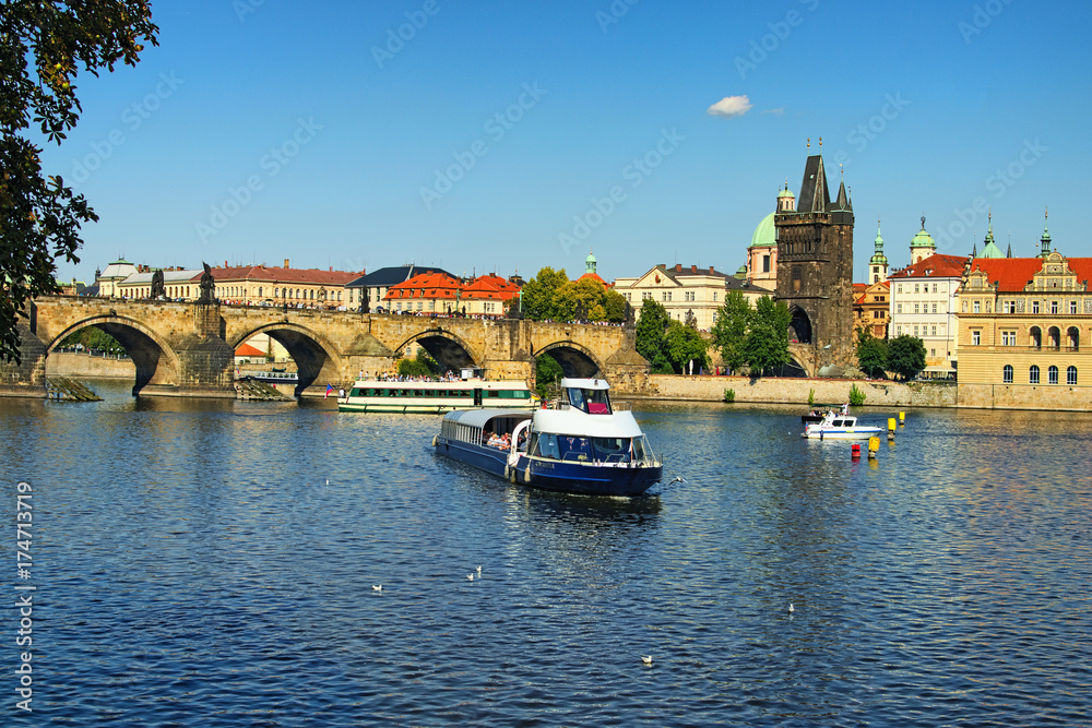 Fototapeta premium Prague, The Czech Republic: AUGUST 23, 2017- A tourist river boat on the Vltava river. View of the buildings and The Charles Bridge