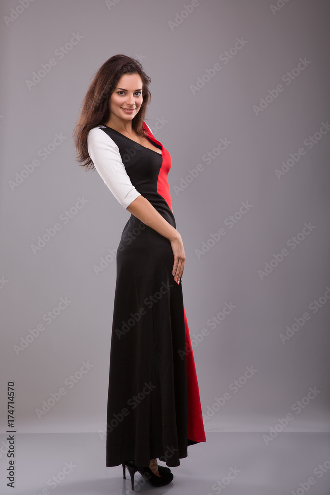 beautiful girl evening long dress posing against gray background beautiful girl evening long dress posing against gray background
